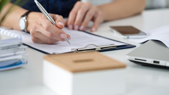 workers compensation lawyers near cortland ny looking over paperwork on clipboard at desk