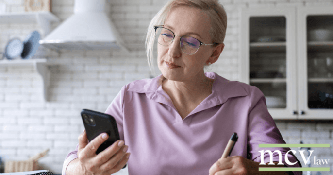what is disability onset date image of woman at home looking at phone while holding pen mcv law logo