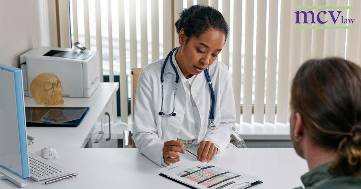 A doctor speaking with their patient looking at a chart at a desk.