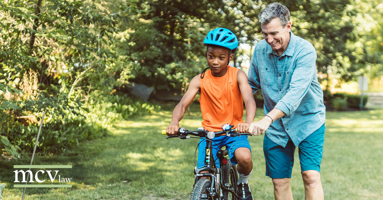 A man walking alongside a child on a bicycle for a blog titled "How to Ask a Loved One to be Guardian to Your Children