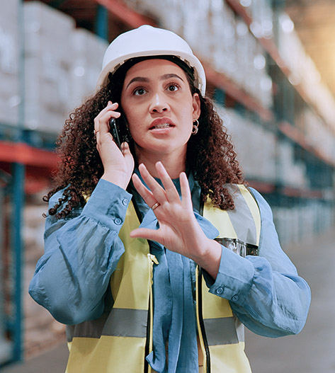 workers compensation lawyers near cortland ny woman on factory floor on phone call looking surprised and frustrated