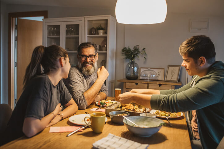 workers compensation lawyers near oneida ny image of family smiling and eating dinner together at home