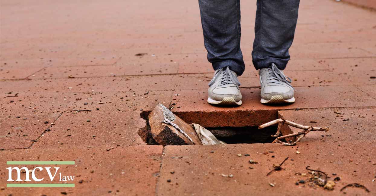 a person's feet on a sidewalk with a hole in it