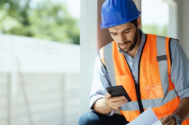 social security disability lawyers near buffalo ny construction worker looking at phone and paperwork
